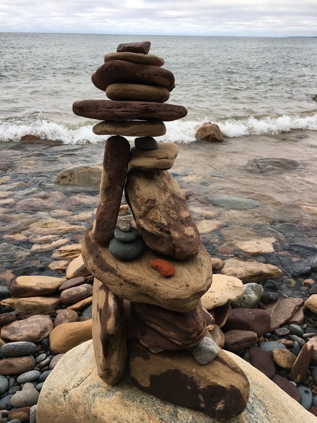 Along a shoreline, someone has stacked rocks to create a small tower