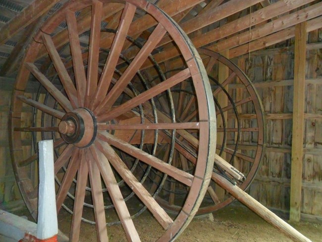 Two large, wooden wheels with a wooden axle in between