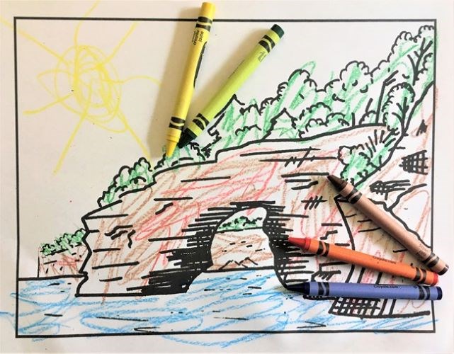 Coloring page of the Pictured Rocks cliffs that has been colored in with crayons laying on top of it.