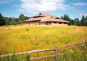 The Lakeshore maintenance building is shown on top of a gentle wildflower covered hill.