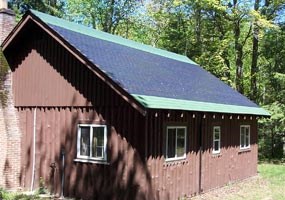 The rustic brown Sullivans Cabin has photovoltaic collector shingles on its roof to power an electric system.