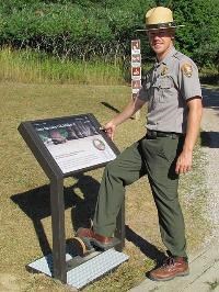 A park ranger using a boot brush station to brush off invasive seeds.