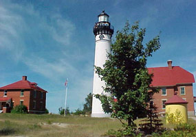 Two red brick keepers quarters flank the whitewashed light tower at the Au Sable Light Station.