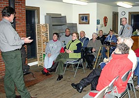 Folks gather around the pot-bellied stove at Munising Falls for a Fireside Chat. Throw another log on the fire!