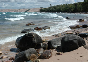 Lake Superior's clear blue water sparkles as the Grand Sable Dunes rise in the distance.