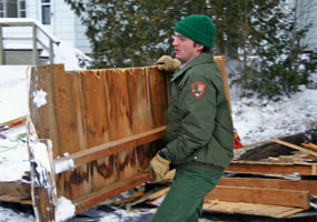 This Maintenance Worker helps remove wood debris from a building demolition project.