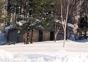 The Munising Falls Interpretive Center is nestled near a shady valley. This winter photo shows it surrounded by white snow.