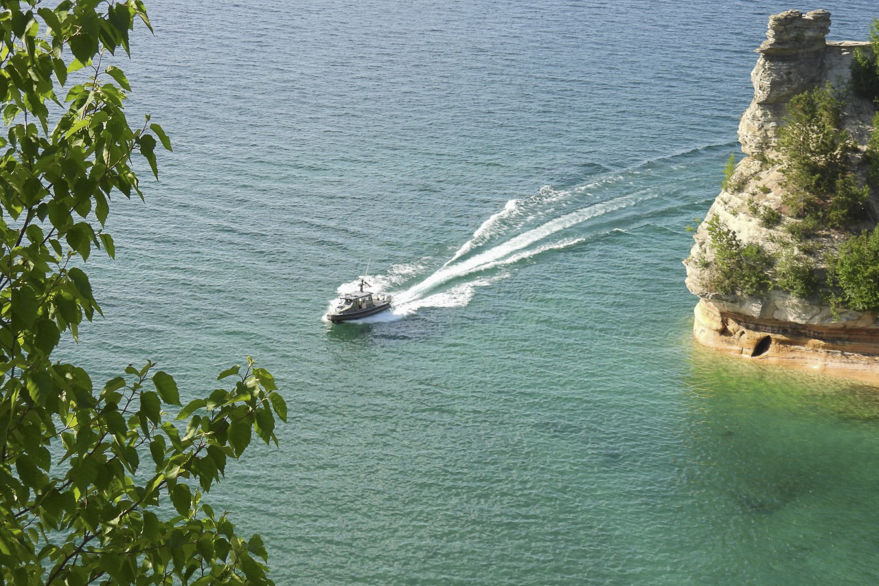 A small patrol boat drives by a sandstone formation