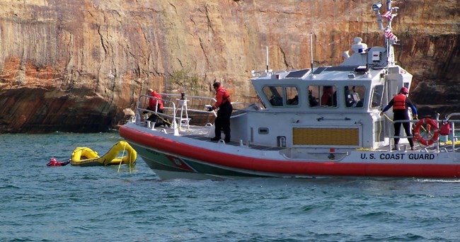 A coast guard boat on Lake Superior sends out a yellow rescue raft.