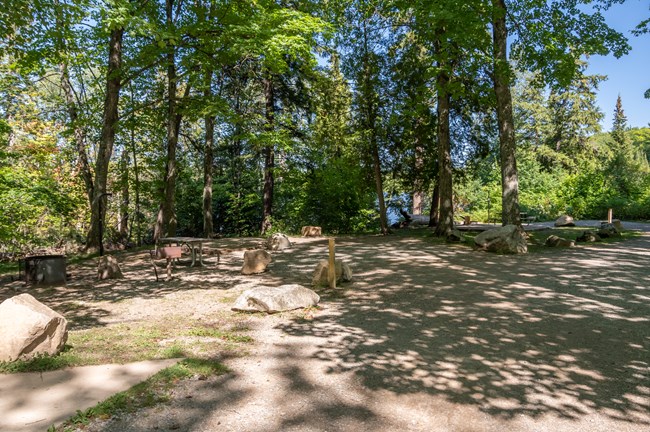 An empty campsite surrounded by large rocks and trees.