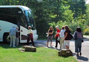 A motor coach and passengers at the Miners Castle parking area.