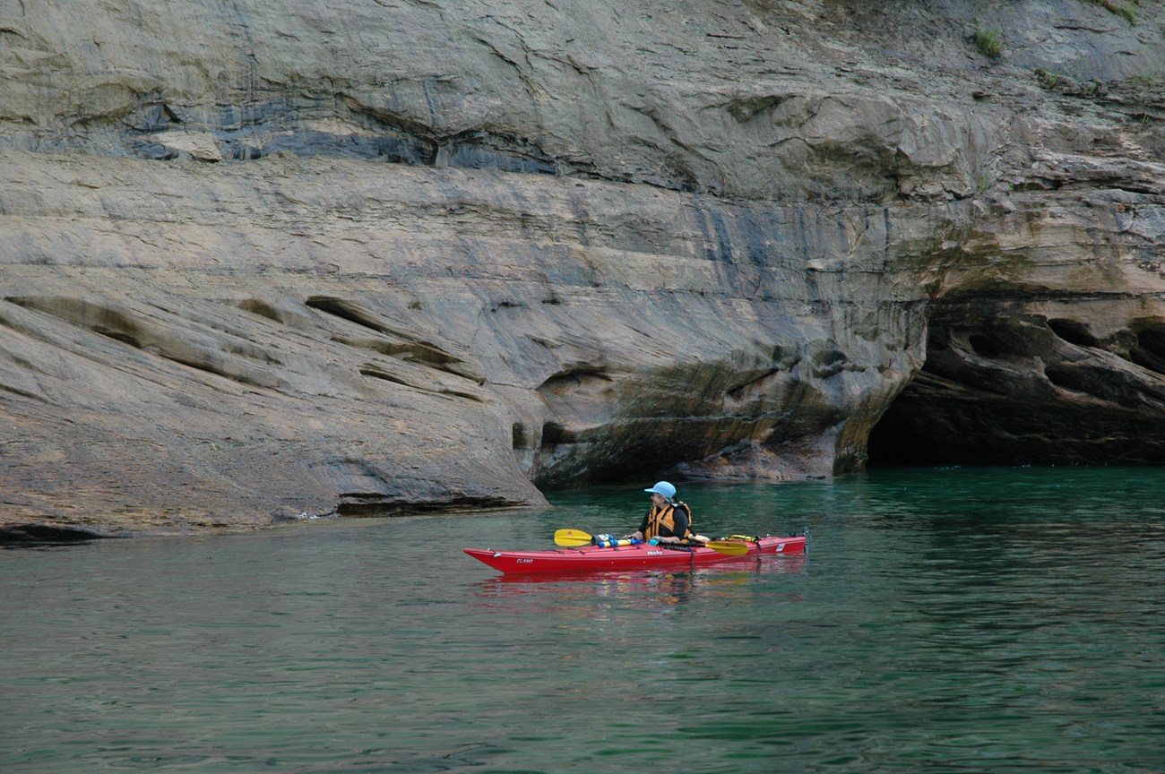 Kayaker on Lake Superior along the Pictured Rocks cliffs.