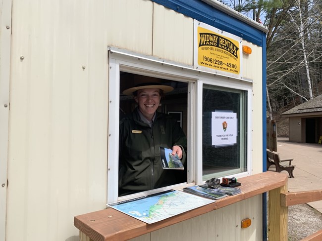 A person stands in a trailer holding a park map out the window.