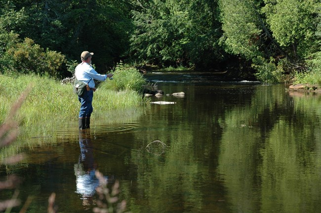Fisherman on river bank flyfishing thebookongonefishing