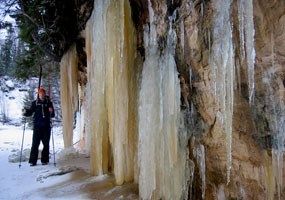 A winter camper took off his skis and posed next to large icicles created from seepage along the Pictured Rocks cliffs.