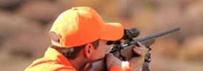 Person wearing hunter orange with rifle
