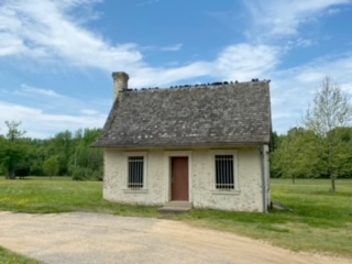 A small one room white building with a gray roof