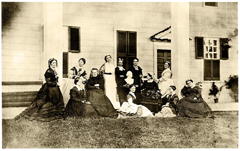 A sepia tone photograph of 12 19th century women and a bust of George Washington in front of Mount Vernon
