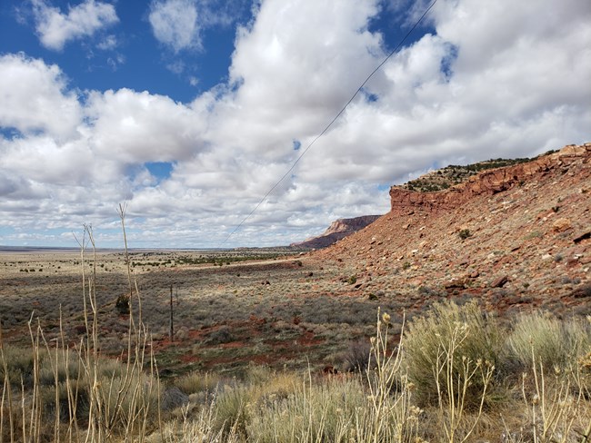 White clouds float above red rock cliffs near Pipe Spring