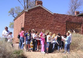 Schoolchildren stand in front of a sandstone fort.