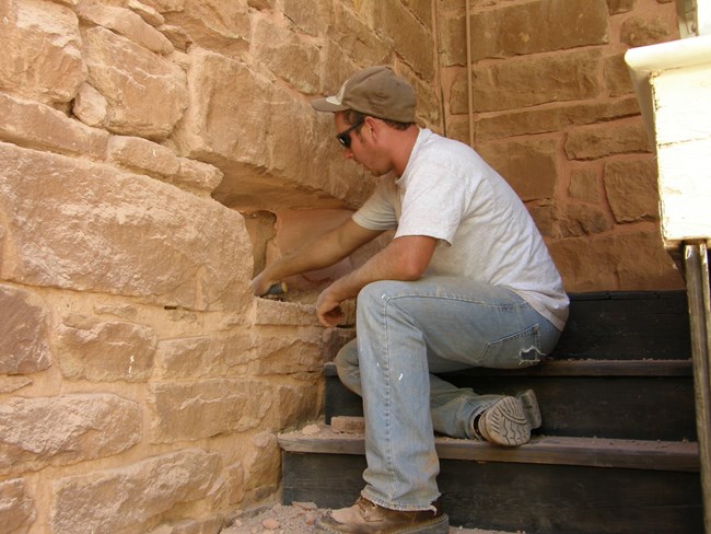 A maintenance worker repoints in a historic fort.