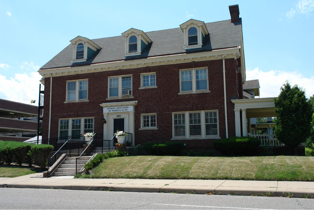 Three-story, brick building with a large white door and a sign above it that reads Detroit Association of Women’s Clubs.
