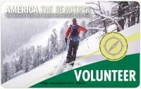 2020_VOLUNTEER PASS A snowboarder gazes at mountain scenery before heading downhill in the snow.