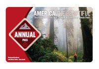 2021 America the Beautiful-The National Parks and Federal Recreational Lands Annual Pass The 2021 America the Beautiful-The National Parks and Federal Recreational Lands Annual Pass with a photo of a hiker looking skyward while standing in a forest of giant redwood trees.