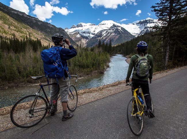 GLAC_Bicyclist Two bicyclists stopped on a paved trail to enjoy the mountain scenery