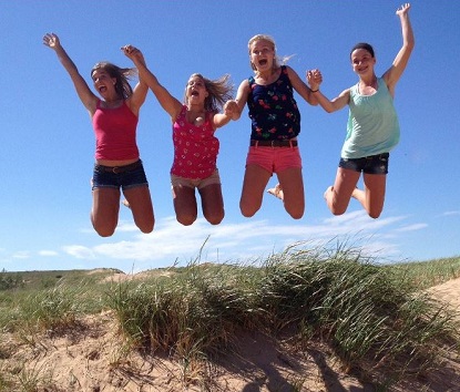 Four women jumping up on a sand dune