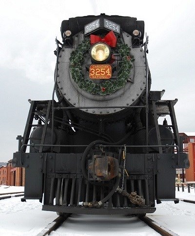 Steam train with a holiday wreath hanging on it