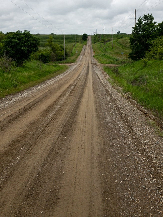 A long, muddy dirt road stretches to the horizon.