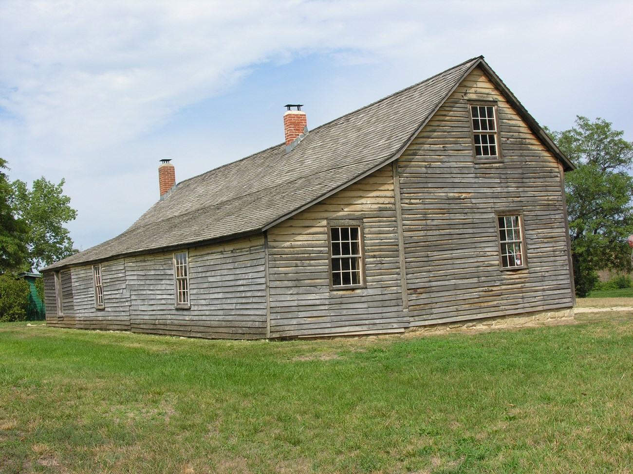A brown wood barn with a slanted, peaked roof.