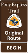 A brown tall rectangular highway sign with white text saying: Pony Express Trail Original Route BEGIN and a triangular logo with orange and white and a blue pony rider. A brown tall rectangular highway sign with white text saying: Pony Express Trail Original Route BEGIN and a triangular logo with orange and white and a blue pony rider.