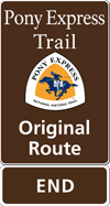 A brown tall rectangular highway sign with white text saying: Pony Express Trail Original Route END and a triangular logo with orange and white and a blue pony rider. A brown tall rectangular highway sign with white text saying: Pony Express Trail Original Route END and a triangular logo with orange and white and a blue pony rider.