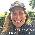 A photo of a smiling woman wearing an NPS volunteer ballcap.