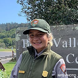 A head photo of Point Reyes Seasonal Park Guide Ruby wearing a gray shirt under a green vest and a green ball cap.