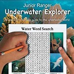 An underwater activity booklet being completed with two hands and a pencil