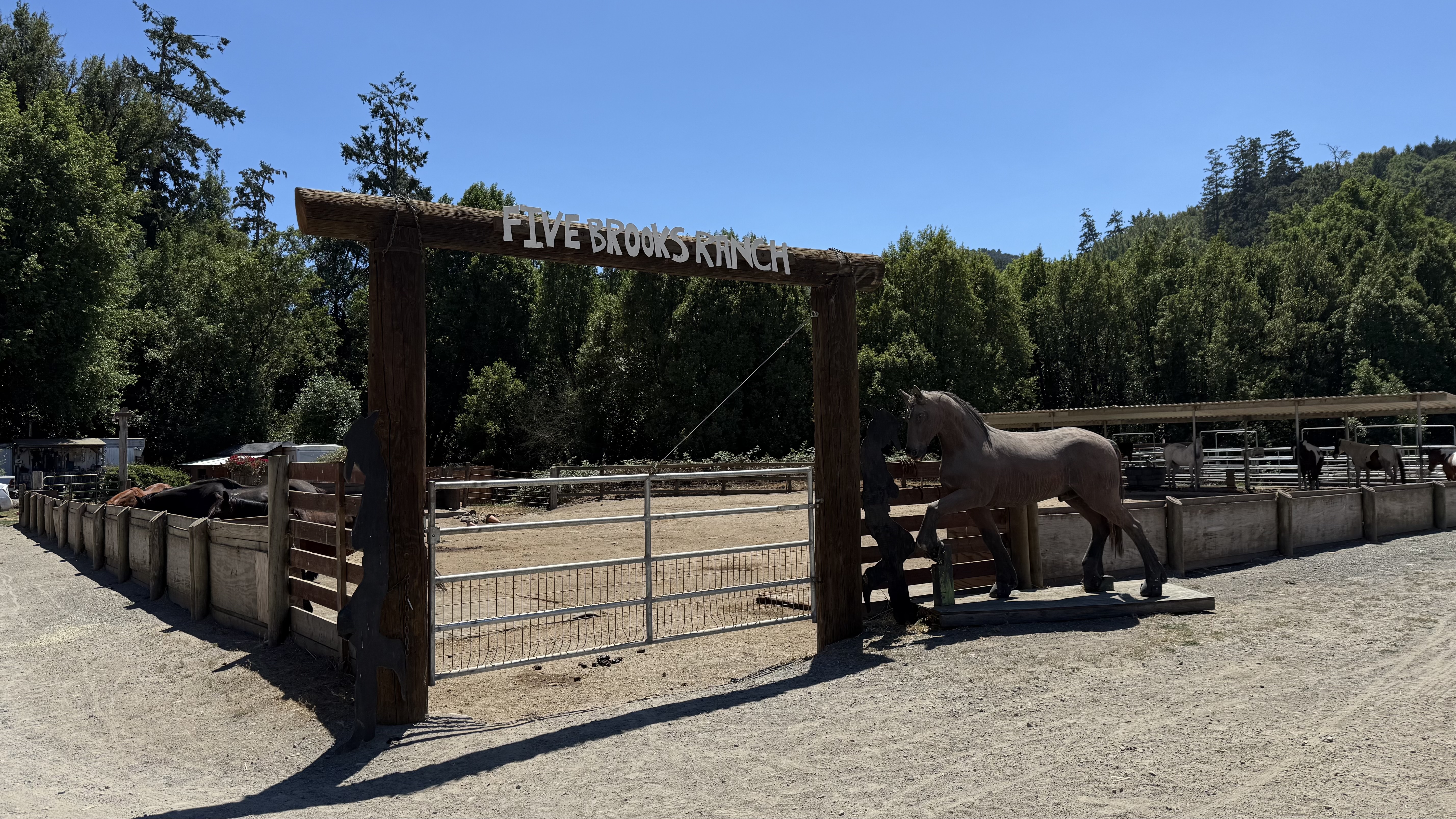A wooden arch over a horse corral that reads Five Brooks Horse Ranch
