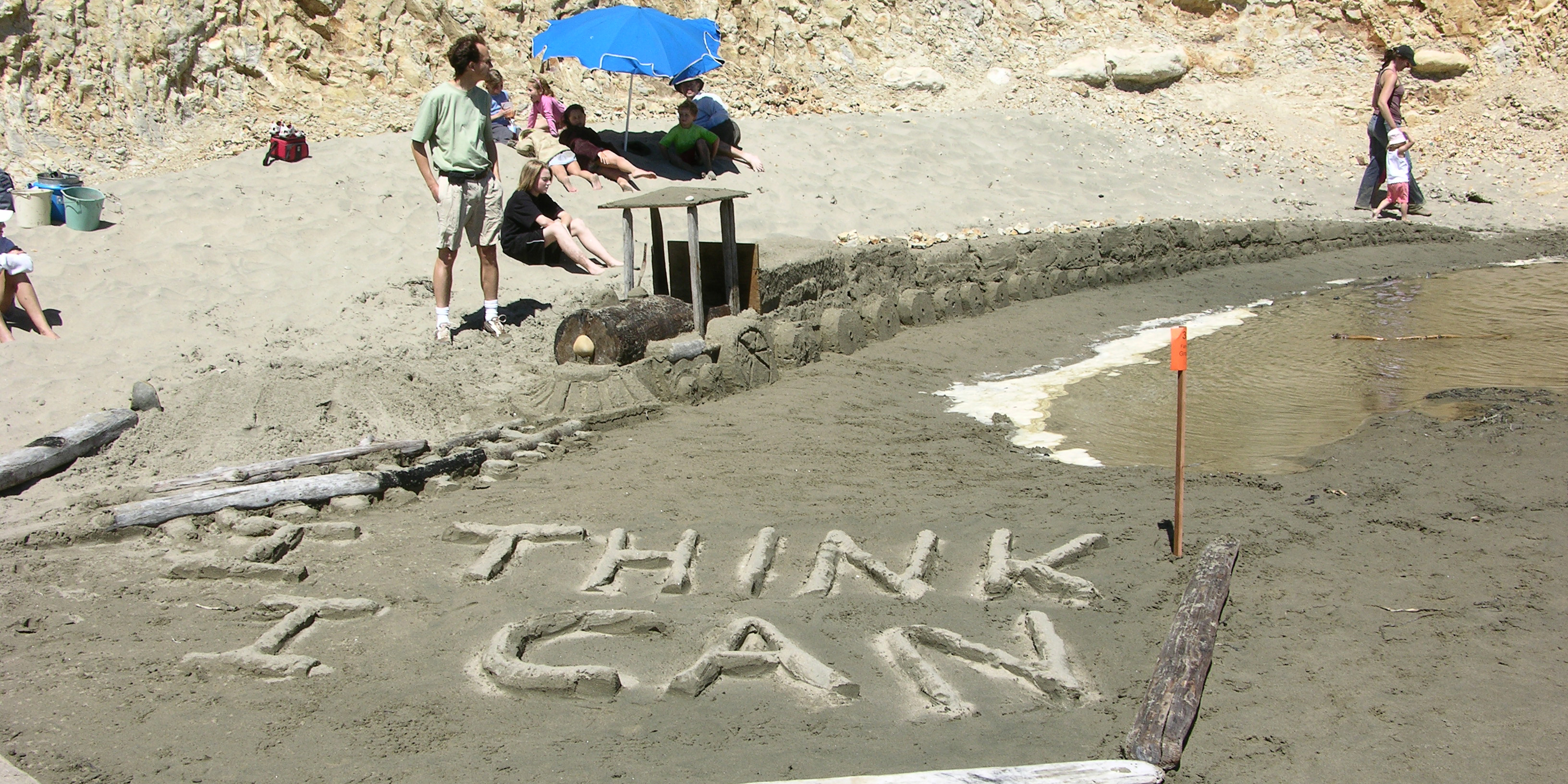 A sand sculpture of a train engine pulling a long line of cars with the words "I Think I Can" in the foreground.