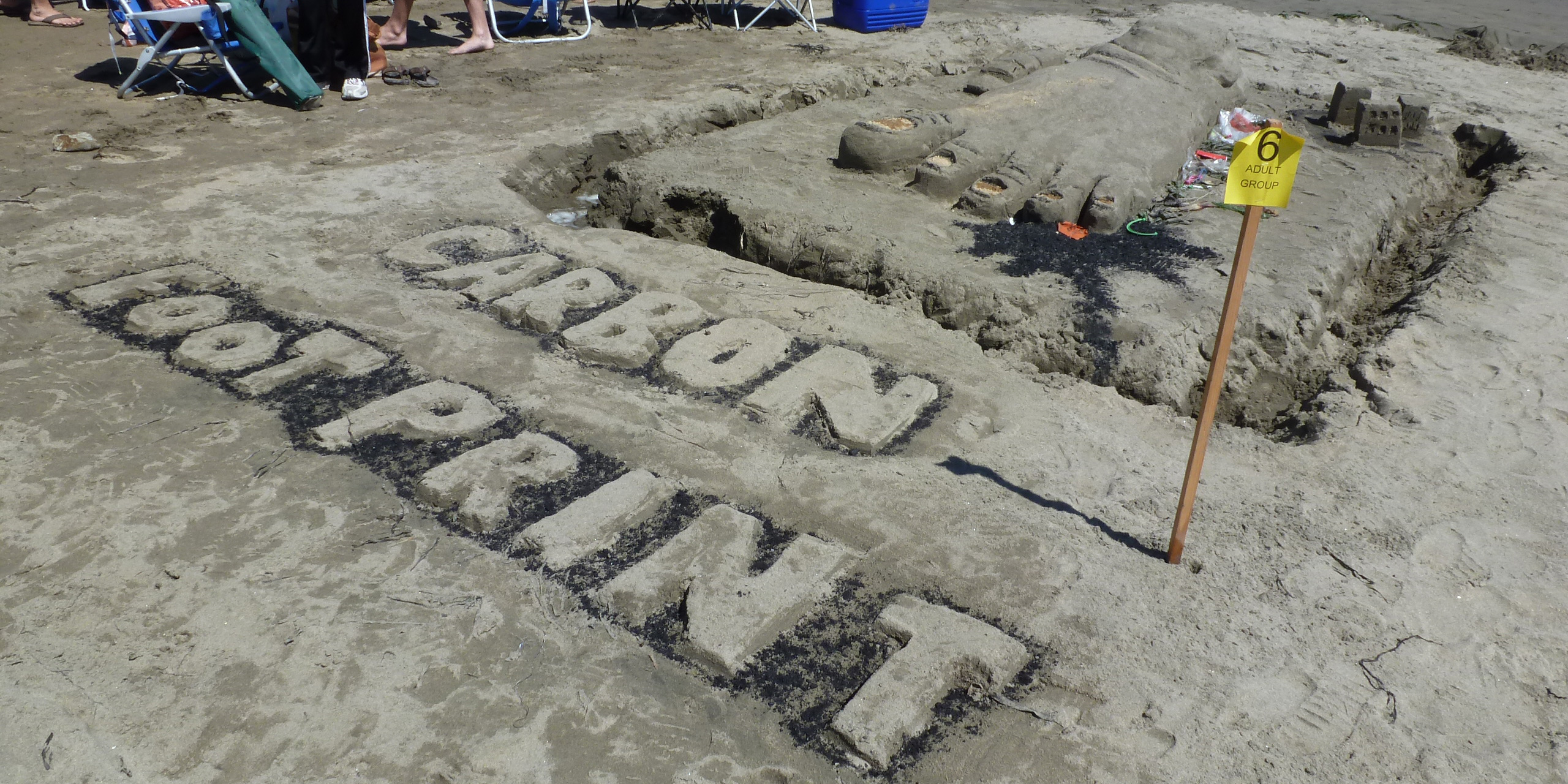 A sand sculpture of a large foot above the phrase Carbon Footprint.
