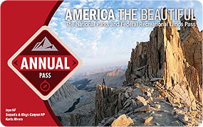Image of the 2023 Interagency Annual Pass, which features a hiker standing at the edge of a mountain clifftop.