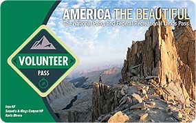 Image of the 2023 Interagency Volunteer Annual Pass, which features a hiker standing at the edge of a mountain clifftop.