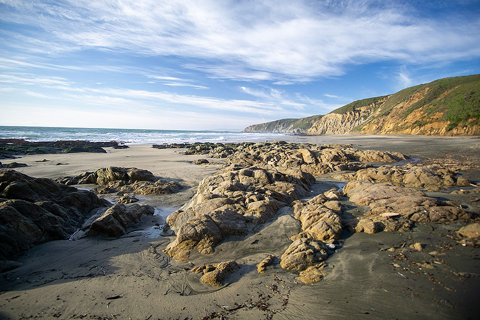 McClures Beach. Low-angle light casts shadows from intertidal rocks on a sandy beach under partly cloudy skies. Low-angle light casts shadows from intertidal rocks on a sandy beach under partly cloudy skies.