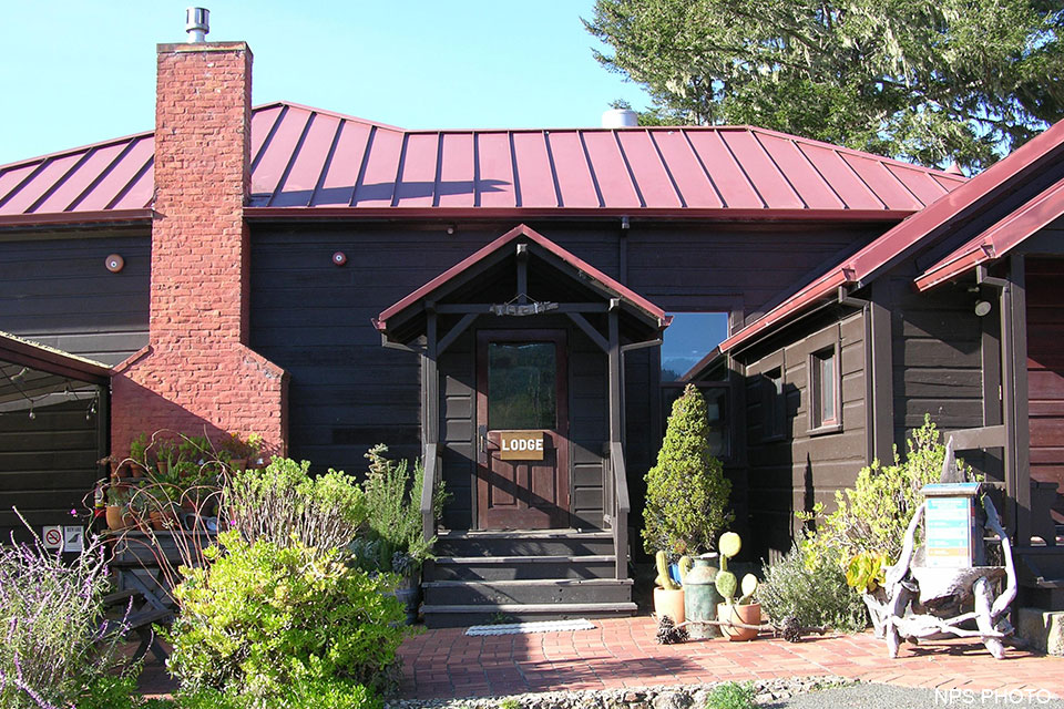 The Point Reyes Hostel's main entrance. A photo of the main entrance to a one-story, brown-sided, red-roofed building.