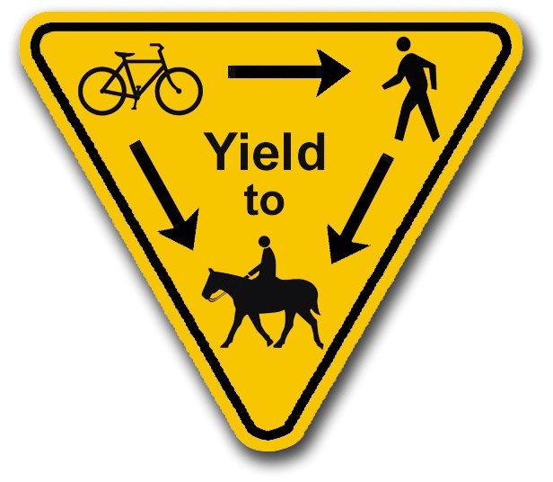 A yellow triangular sign indicating bicyclists a required to yield to hikers and both bicyclists and hikers are required to yield to horse riders.