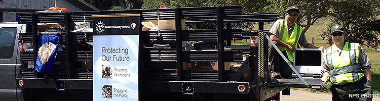 Two uniformed park employees loading electronic waste into a gray stake bed truck. Two uniformed park employees loading electronic waste into a gray stake bed truck.
