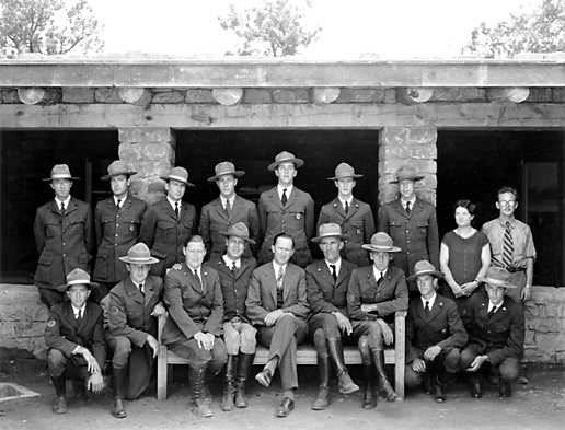 Rangers and other staff seated and standing in front of a building.