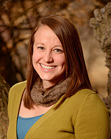 A woman with long brown hair wearing a scarf and sweater