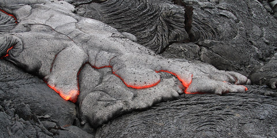 red lava glowing under black rocks